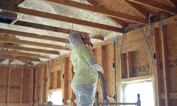 Person applying spray foam insulation indoors